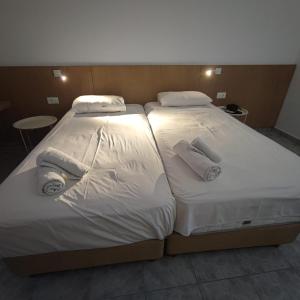 two beds in a room with white sheets and towels at Sea View Luxury Studios in Vrachonisída Palaiókastro