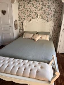 a white bed in a bedroom with floral wallpaper at La périgourdine et son spa in Saint-Cyprien