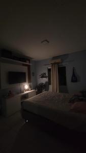 a dark bedroom with a bed and a television at Casa 3 Quartos in Ananindeua
