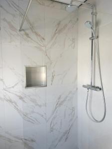 a shower in a bathroom with white marble walls at Blom studio's in Hillegom +38 photos