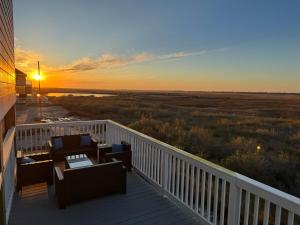 a sunset on a deck with chairs and tables at Jelly Bay in Bolivar Peninsula