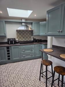 a kitchen with blue cabinets and a table and stools at Newly Refurbished Townhouse in Derry Londonderry