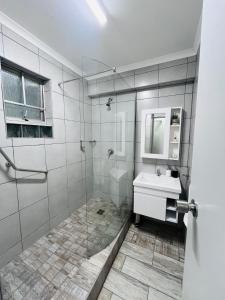 a bathroom with a shower with a sink and a mirror at Ushaka Ocean Escape - Shaka Shores 5E in Durban