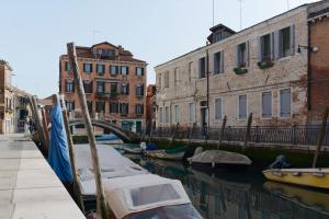 two boats are docked in a canal next to buildings at Domus Dea in Venice