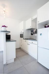una cocina blanca con armarios y electrodomésticos blancos en Studio Marine du Soleil, en Patrimonio