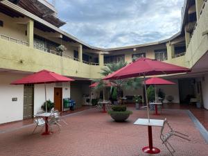 a courtyard with red umbrellas and tables and chairs at Hotel Primavera in Floridablanca