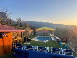 um quintal com uma piscina com cadeiras e um guarda-sol em Quinta do Sonho em Resende