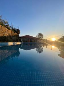 uma piscina com o pôr do sol ao fundo em Quinta do Sonho em Resende
