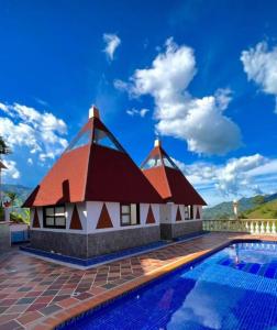 a house with a thatched roof next to a swimming pool at Finca Hotel Villa Tara in Barbosa
