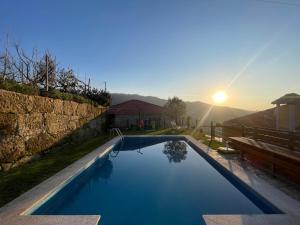 uma piscina num quintal com o pôr-do-sol ao fundo em Quinta do Sonho em Resende