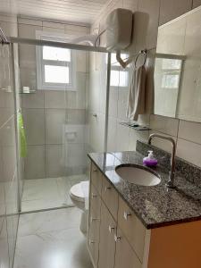 a bathroom with a sink and a shower and a toilet at Casa Zanata in Gramado