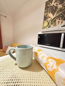 a coffee cup sitting on a table next to a microwave at Le Tiny Studio in Saint-Denis
