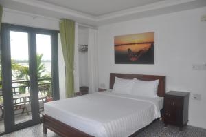 a bedroom with a white bed and a balcony at Autumn Bay Retreat in Hoi An
