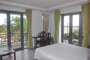 a bedroom with a bed and a balcony with windows at Autumn Bay Retreat in Hoi An