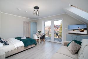 une chambre avec un lit, une télévision et une table dans l'établissement Róża Bałtyku - Apartamenty i Pokoje B, à Dębki