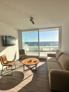 a living room with a couch and a table at Depto privado con vista despejada al mar en 1 línea, terraza 20 mts y estacionamiento con acceso desde el borde costero in Vina del Mar