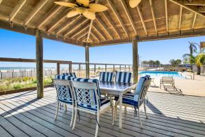 a deck with a table and chairs and a pool at TB Beach House in Dauphin Island