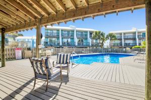 a deck with two chairs and a swimming pool at TB Beach House in Dauphin Island