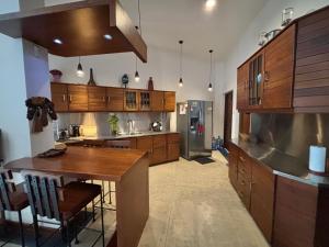 a large kitchen with wooden cabinets and a wooden table at Villa Plum Colombo in Battaramulla