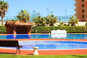 a bench in front of a swimming pool with a fountain at New Juncos 2 Planetcostadorada in La Pineda