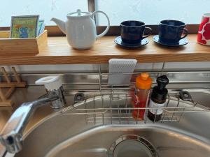 Un escurridor de platos sobre un fregadero con dos tazas de café en 伊勢志摩観光に最適 パールロードの玄関口 PAARU inn 2階B室 セルフチェックイン, en Toba 22 fotos más