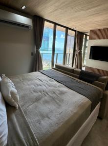 a bedroom with a large bed with a large window at Apto Beira-Mar com Vista Mar - NT1206 in Maceió