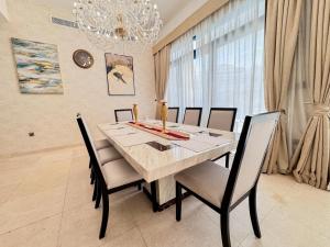 a dining room table with chairs and a chandelier at Estatesmen Palm Jumeirah Luxury Family Friendly Villa in Dubai