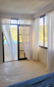 a bedroom with white curtains and a large window at Studio apartment in the mountains in Santa Marta