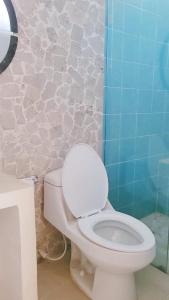 a bathroom with a white toilet and a blue wall at Room with private bathroom in Taganga