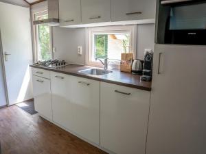a kitchen with white cabinets and a sink and a window at Farmhouse in Veluwe near Speulderbos in Ermelo