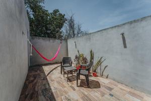a patio with two chairs and a table with a red hose at Habitacion Privada, 5 min Catedral in Mérida