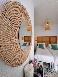 a bedroom with a large wicker mirror on the wall at Villa Acqua en front de mer in Nabeul