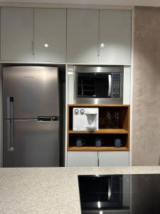 uma cozinha com geladeira e micro-ondas em Guarapari Apart1315 em Guarapari