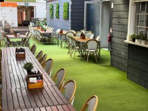an outdoor patio with tables and chairs and green grass at The Hampden Suites in Wagga Wagga