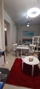 een woonkamer met een tafel en een rood tapijt bij Studio στο κέντρο του Βόλου in Volos