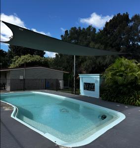 a swimming pool with an umbrella in a yard at Murgon Motor Inn in Murgon