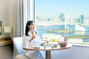 a woman sitting at a table with a glass of wine at Grand Nikko Tokyo Daiba in Tokyo