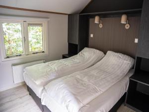 a large bed in a room with a window at Pets Welcome, Veluwe Farmhouses for All in Ermelo