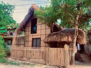 a house with a thatch roof and a fence at General Luna Guest House in General Luna