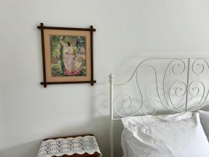 a bedroom with a white bed and a picture on the wall at Grandad's farmhouse in Northcliffe