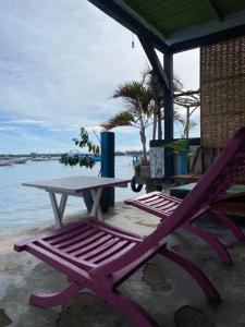 a picnic table and two chairs next to the water at RGJS2r Hostel KARIMUNJAWA in Karimunjawa