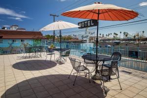 un patio con mesas, sillas y una sombrilla en Aqua Breeze Inn en Santa Cruz