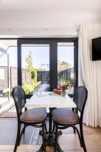 a dining room with a table and chairs and windows at Potager B&B- Waiohine- Greytown in Greytown