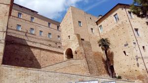 un grand bâtiment en briques avec un arbre devant lui dans l'établissement La Casa Sul Borgo, à Lapedona