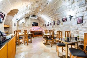 a restaurant with wooden tables and chairs and a stone wall at hotel Louvre Sainte Anne in Paris