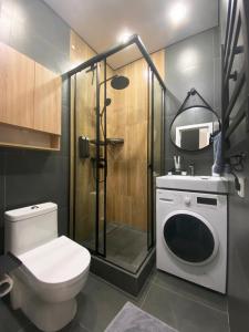 a bathroom with a toilet and a shower with a washing machine at Contento Apartments in Almaty