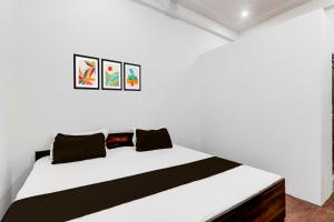 a bedroom with a white bed with three pictures on the wall at Hotel O S.M NAINI HOTEL AND RESTAURANT in Prayagraj
