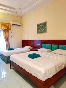 two beds in a room with two at Dewi Ratih Hotel Batang in Batang +11 photos