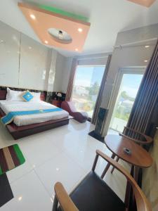 a bedroom with a bed and a table and a chair at Khách Sạn Sapphire in Gò Công
