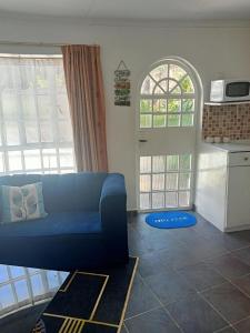 a living room with a blue couch and two windows at Evergreen Karen Guesthouse in Nairobi
